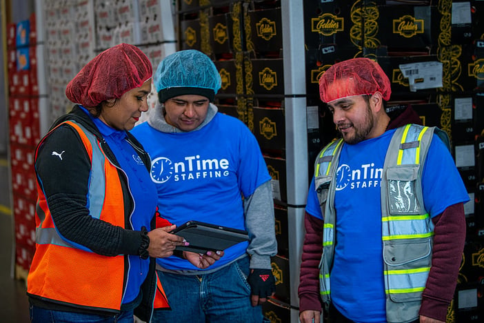 Group of workers holding a tablet in a warehouse